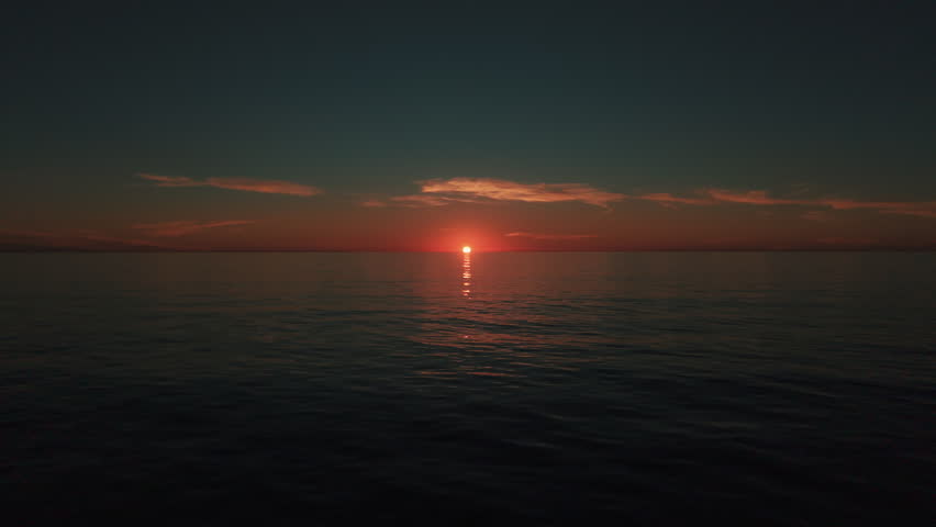 Drone aerial of California sunset over Pacific Ocean with vibrant colors reflecting on water and peaceful coastal horizon