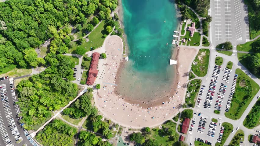 An area that is reserved for family fun as many people can be seen heavily populating the beach front of this lake.