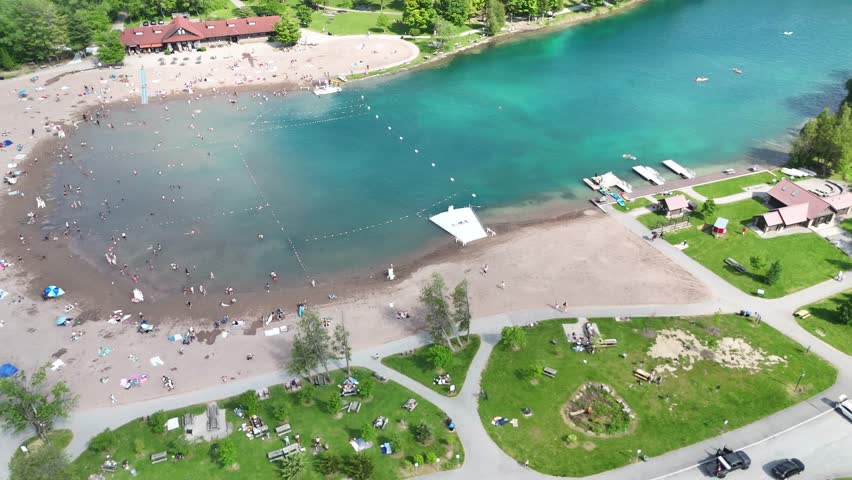 Many people utilizing the beach at this state park as numerous individuals are scattered across the sand and in the water swimming.