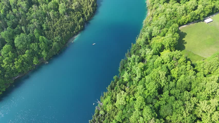 People kayaking and canoeing within a lake delineated by forest on every side.