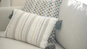 Close up shot of decorative throw pillows on light gray couch. Dynamic zoom out reveals cozy interior with wicker chair. - Powered by Shutterstock - Get 15% off with code: PIKWIZARD15