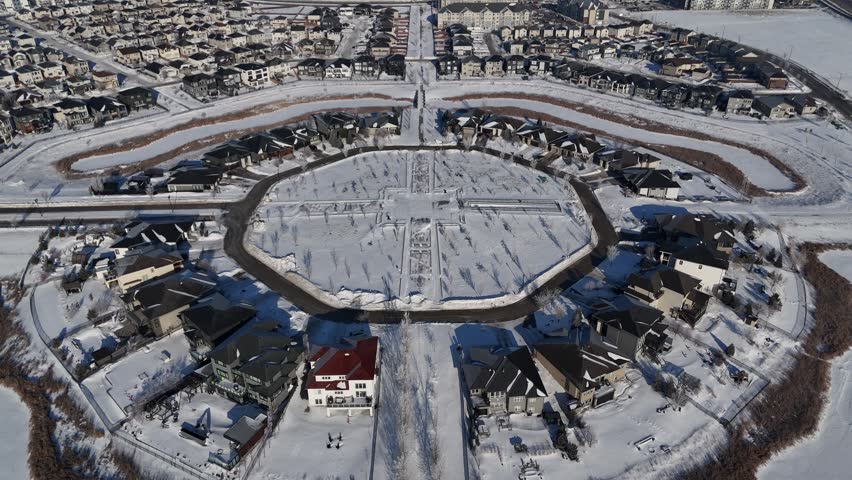 Aerial drone shot orbiting right over Bridgwater Trails Centre park area in Winnipeg Manitoba. Shows houses, drainage ponds, and surrounding neighbourhood in winter.