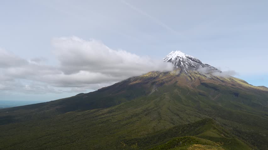 Aerial panning view of Mount Taranaki landscape under cloudy sky New Zealand natural travel destination