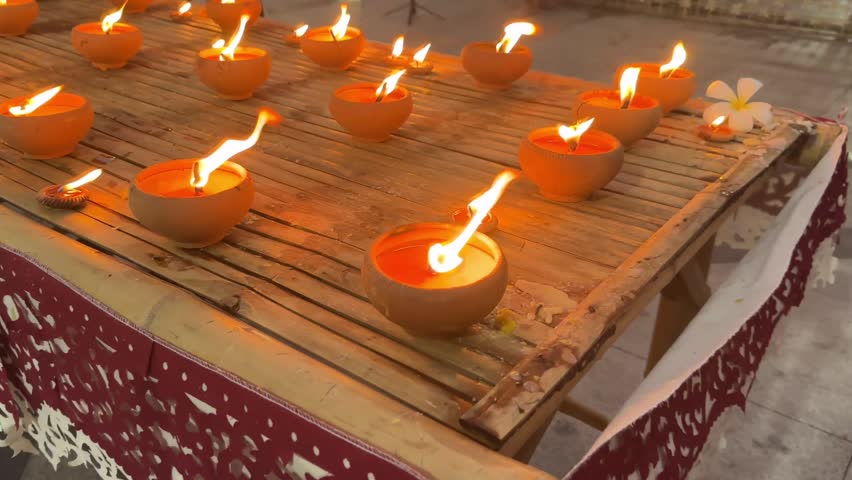 Video of clay oil lamp with warm flame on wood surface, symbolizing peaceful ritual and festive atmosphere