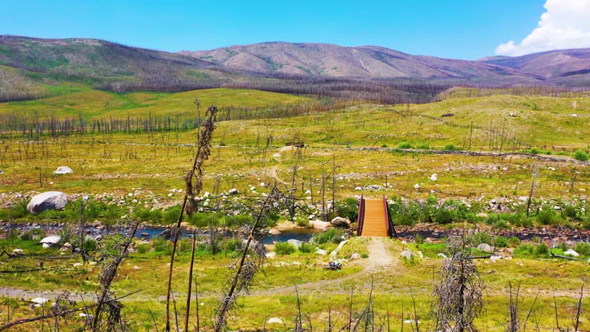 Scenic aerial panorama of post fire wilderness in Rocky Mountain National Park Colorado, with sparse burned trees, rolling grassland, rugged hills, and distant alpine ridges.