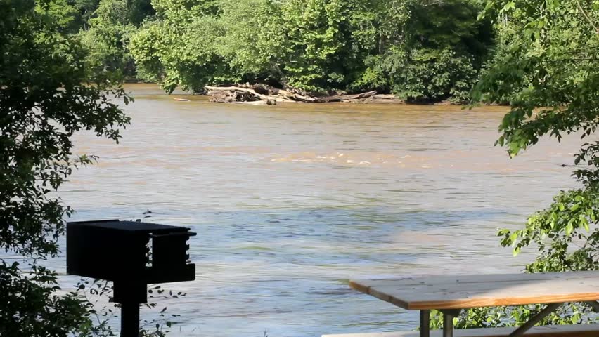 Picnic Table And Empty Grill By A Slow Flowing River