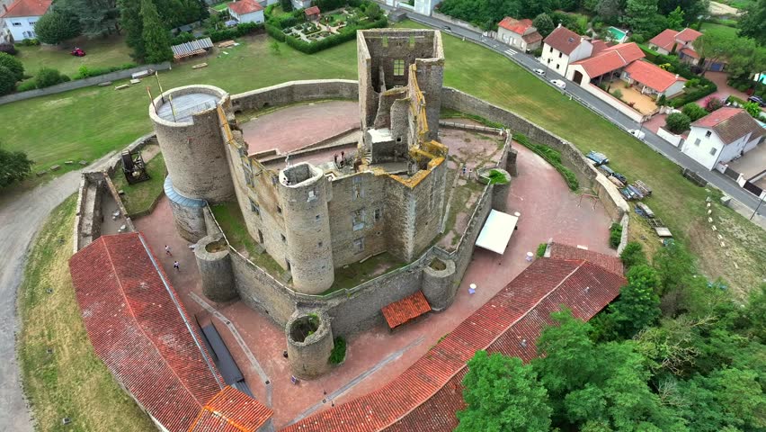 Drone footage focusing on an ancient stone tower and castle ruins in France. Detailed medieval architecture with defensive walls and historic structure. Perfect for cultural and historical themes.