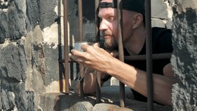 Arrested young man eagerly drinks water from cup reaching hands through bars, handcuffed to iron prison bars. Detainee quenches thirst in prison. Illegal migrant asking for water Prisoner very thirsty - Powered by Shutterstock - Get 15% off with code: PIKWIZARD15
