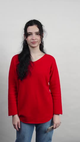 Young brunette woman in red sweater making a call me gesture on a white background