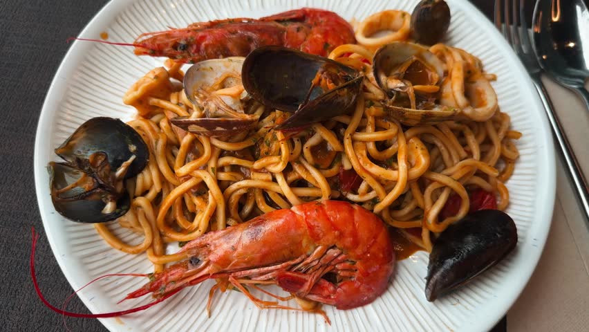 A plate of seafood pasta in tomato sauce served at an Italian restaurant. Traditional cuisine and lunch concept.
