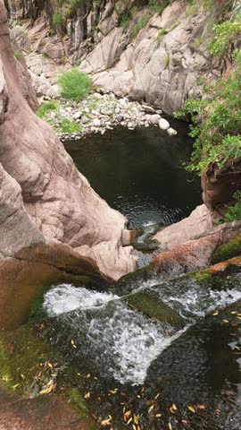 Waterfall among rocks and natural pool in a mountain canyon
