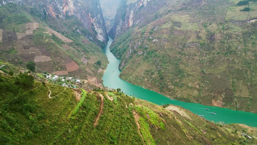 Aerial drone footage of massive limestone cliffs rising above a narrow river carving through a deep canyon showcasing powerful geological formations and raw natural terrain