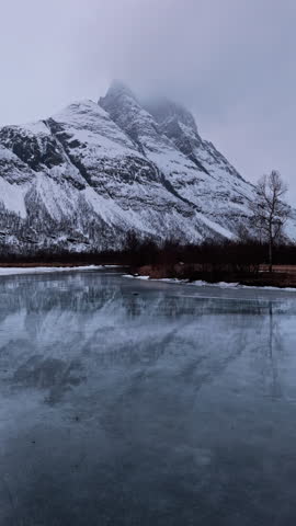 Snowy mountain with icy lake reflecting calm winter scene