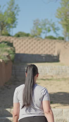 Back view of a young woman climbing stairs in a green nature park