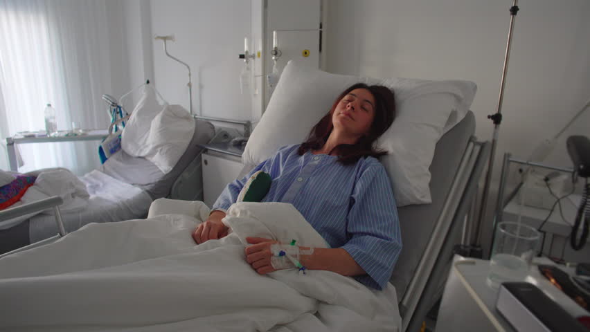 Scene of woman lying in hospital bed surrounded by medical equipment conveying postoperative care, healing process and calm resting state after procedure
