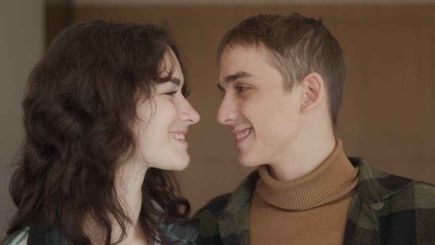 A close up shot of a young man and woman looking at each other lovingly before showing their new house keys to the camera in their modern kitchen during move.