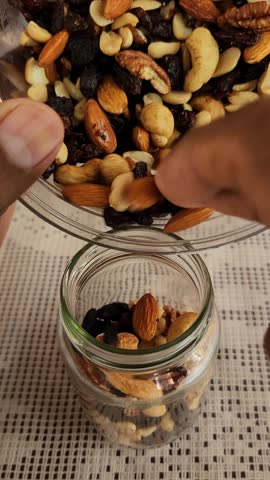 Pouring mixed nuts into a glass jar for storage