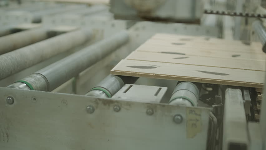 A large industrial warehouse featuring a forklift operating among stacks of dried wooden planks prepared for further furniture or flooring production