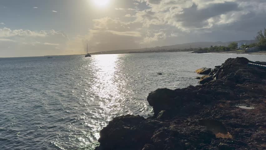 Cinematic 4K wide shot of the tropical Caribbean coastline in Puerto Rico, featuring the blue ocean horizon, rocky shores, and scenic coastal views under a clear bright sky.
