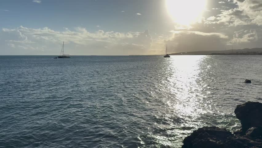 Cinematic 4K wide shot of the tropical Caribbean coastline in Puerto Rico, featuring the blue ocean horizon, rocky shores, and scenic coastal views under a clear bright sky.