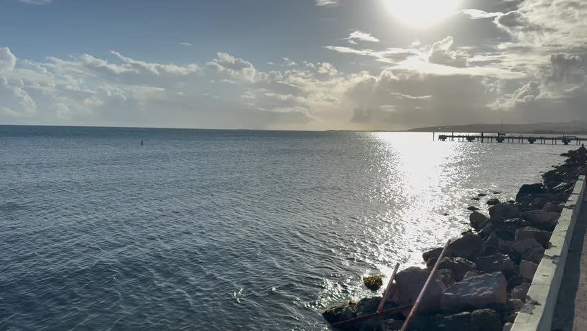 Cinematic 4K wide shot of the tropical Caribbean coastline in Puerto Rico, featuring the blue ocean horizon, rocky shores, and scenic coastal views under a clear bright sky.