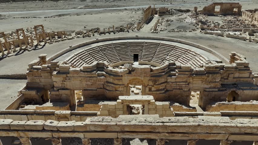 Cinematic aerial view of the remarkably preserved Roman Theatre in the archaeological site of Palmyra