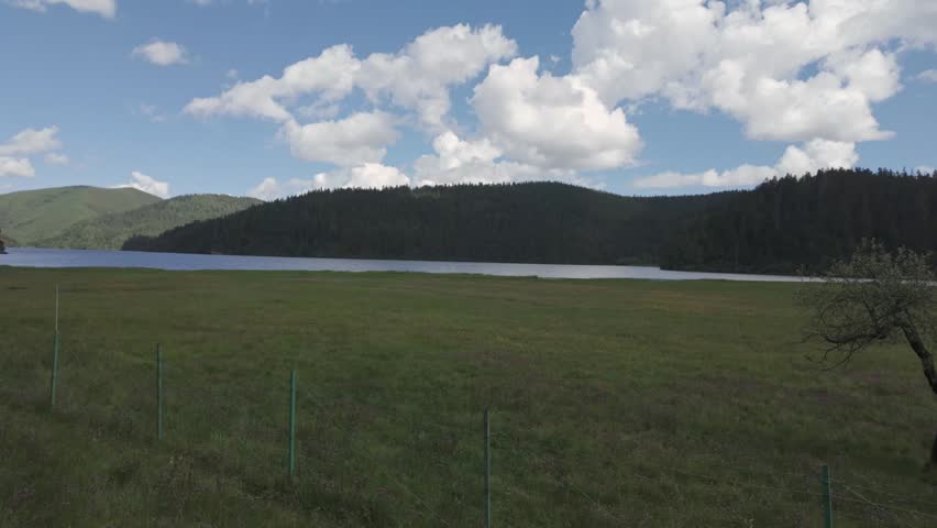 Lake shoreline with grass meadow forest hills and clouds in Potatso National Park Yunnan, establishing static
