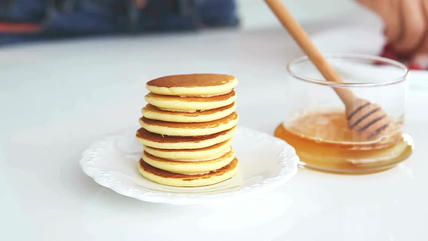 putting honey or jam on pancakes with raspberries. tasty pancakes with berries. A stack of fluffy breakfast American pancakes with fresh raspberries.