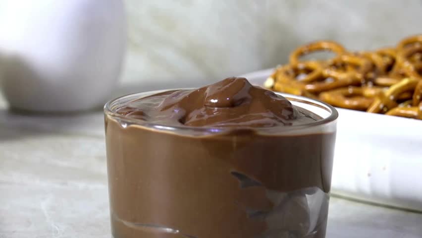 Hand Dipping a salted mini pretzel into melted milk chocolate sauce. Chocolate sauce and salted pretzels. Tasty mini pretzel with dark chocolate dipping sauce.