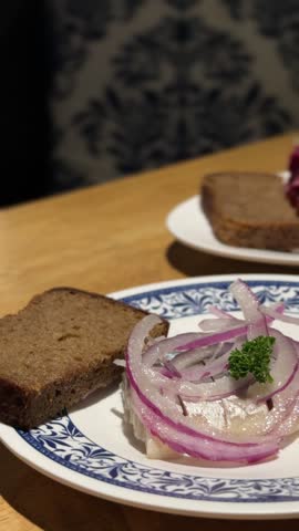 Traditional Russian feast in a cozy cafe: table set with red borsch, Olivier and Herring under a fur coat salads, salted fish with red onion and rye bread. Authentic hearty Slavic meal and banquet.