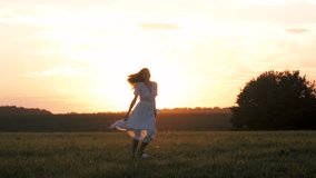 Silhouette of happy young woman in flowing white dress spinning and dancing in a grassy field. Female celebrating freedom and joy against beautiful golden light of sunset sun at spring - Powered by Shutterstock - Get 15% off with code: PIKWIZARD15