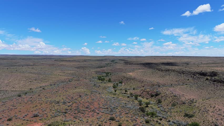 Flying over dry riverbed in arid savanna of Namibia, Africa, showcasing immense wild natural landscape of untamed wilderness under vast blue sky