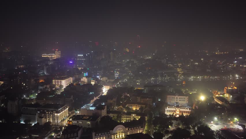 Aerial illuminated cityscape of Hanoi, Vietnam during a vibrant night, showing downtown skyline, streets with traffic from an aerial position