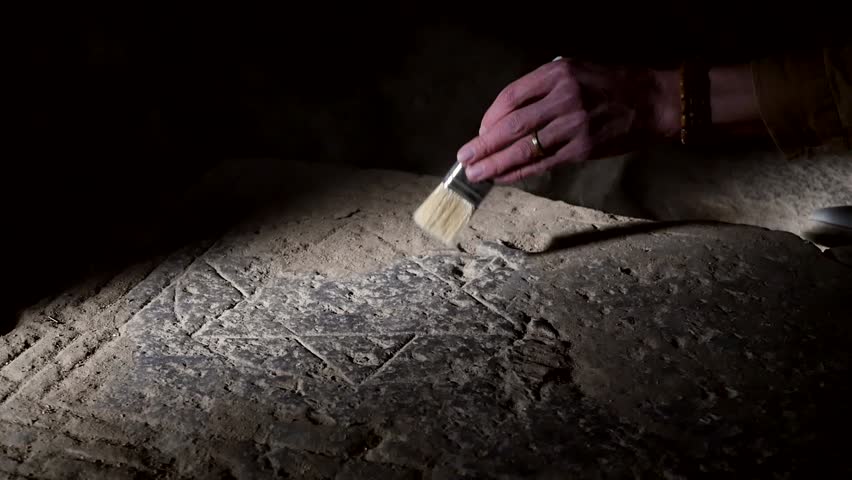 Archaeologist discovered Star of David carved in rectangular stone slab resembling tombstone. Scientist uses brush to remove dust from archaeological find. Ancient Jewish territories. Ancient Israel.
