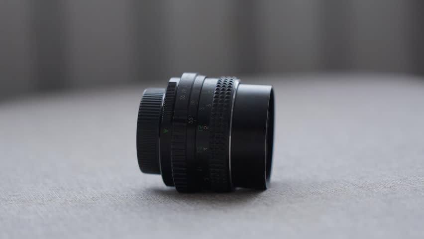Vintage Style Manual Camera Lens With Aperture Rings And Textured Focus Handle. Oldtime Manual Camera Lens Mounted On Gray Surface Showing Aperture Controls And Textured Focusing Grip