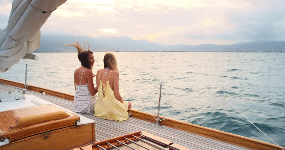 Friends, back and women on yacht in ocean for vacation, tropical adventure and tourist destination. Sunset, nature and people relax on boat for cruise, journey and explore islands on summer holiday