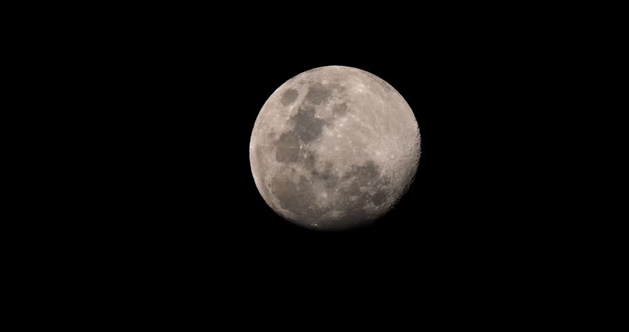 Full moon shining in a clear black night sky showing detailed lunar craters and surface texture. Close-up telephoto shot of the moon during night.