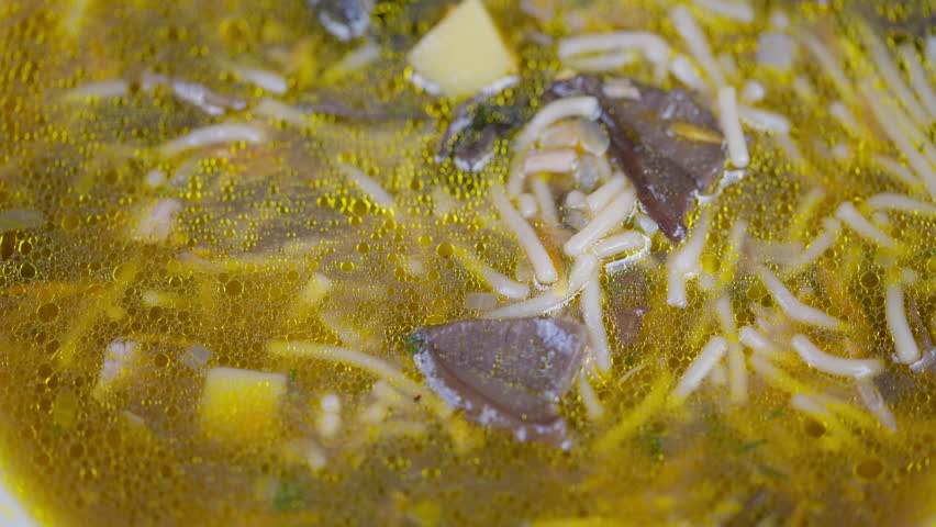 Closeup of flavorful noodle dish. Hot broth with mushrooms and herbs captured in detail. Vivid macro shot of savory mushroom noodle soup with floating ingredients