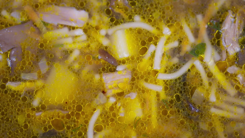 Golden broth with noodles and mushrooms. Closeup of aromatic mushroom noodle soup in oil. Comforting dish featuring mushroom noodles in fragrant amberhued savory broth with herbs