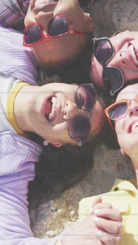 Vertical video: 4 women lying heads touching on sand, red heart drawing over faces sparking joy ads. Friendship, togetherness, outdoor, beach, summer, casual, vertical video