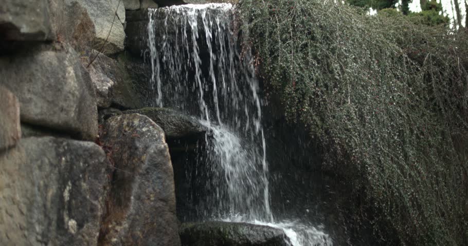 a small mountain stream or waterfall of crystal clear cool spring fresh water flows among stones and rocks