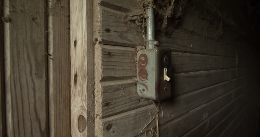 Close up of a vintage electrical switch mounted on a rustic wooden barn wall in Brookville Indiana. Atmospheric farm interior detail showing aged textures and rural utility elements.