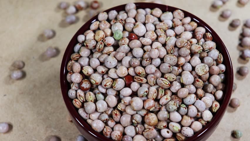 Pigeon pea (Cajanus cajan) seeds in a ceramic bowl rotate on a wooden table in Brazil.