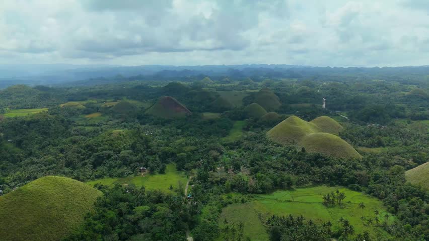 A drone pulls back over the Chocolate Hills on a sunny day in Bohol