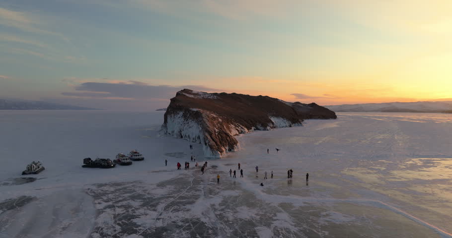 Ogoy island in winter Baikal lake, Siberia, Russia. Aerial view. Tourists walking around the island. Cars and hovercrafts ride on the ice. Winter landscape