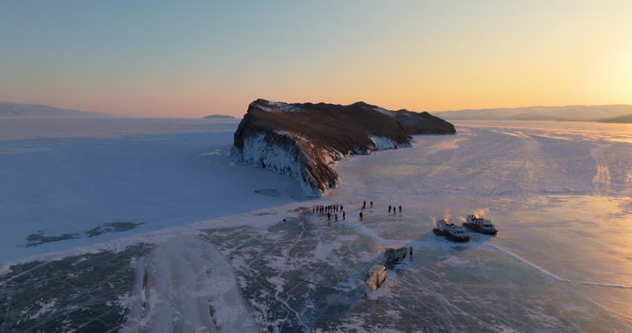 Ogoy island in winter Baikal lake, Siberia, Russia. Aerial view. Tourists walking around the island. Cars and hovercrafts ride on the ice. Winter landscape