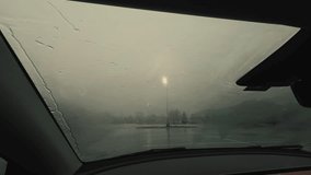 Fogged car windshield during heavy rain, reducing visibility while driving. Moisture and condensation on glass create dangerous road conditions and blurred view of street lights. - Powered by Shutterstock - Get 15% off with code: PIKWIZARD15