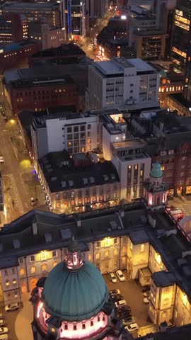 Reversing overhead 4K 60FPS aerial GV of Belfast City Hall in Belfast City Centre, Northern Ireland at night. Produced with Rec709 color.