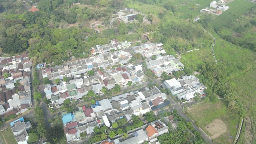 Aerial view of a packed suburban housing estate bordering a misty mountain and lush green valley.