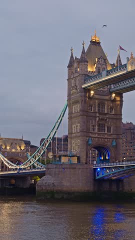 Iconic tower bridge in london stands illuminated at dusk, thames river flowing calmly below.